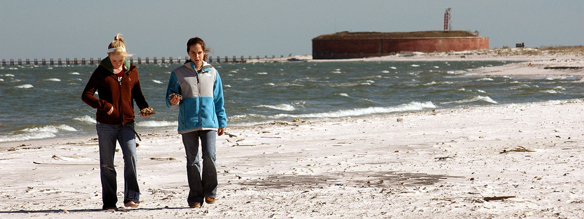 Wanderer am Strand von Ship Island mit Fort Massachusetts im Hintergrund